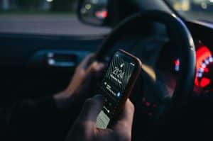 man with one had on steering and the other holding a phone
