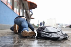 man-with-backpack-lying-slippery-sidewalk-after-fall-closeup