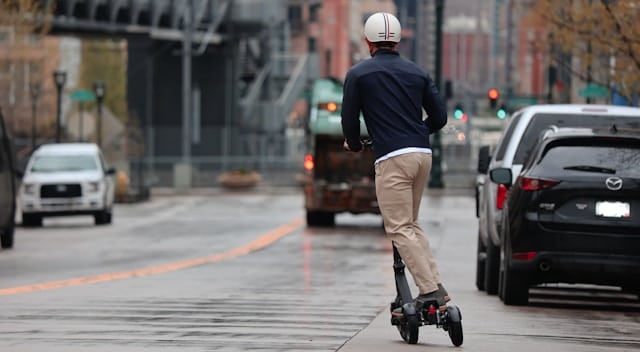 man riding an e-scooter in a road