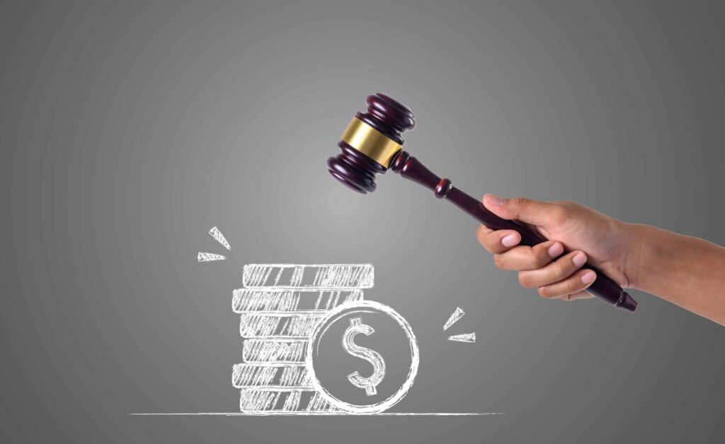 The hand that holds the hammer and piles of money written with white chalk, draw concept.