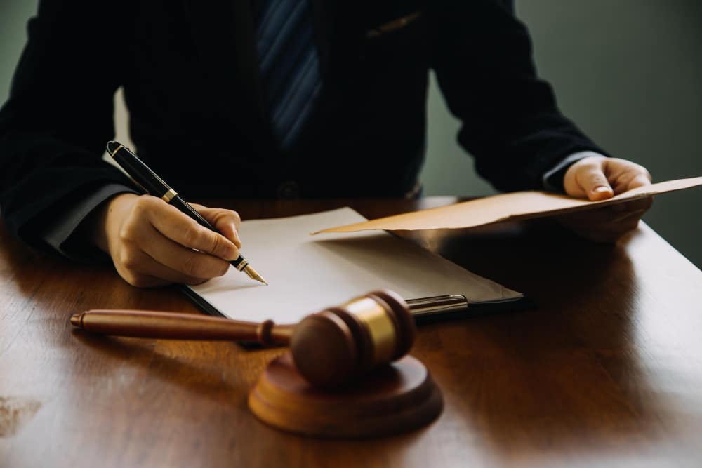 Business and lawyers discussing contract papers with brass scale on desk in office