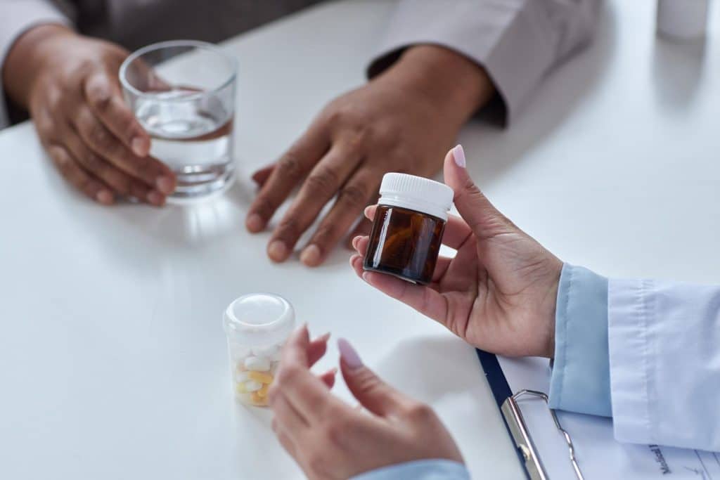 Close up of female doctor holding bottle of pills and explaining medication
