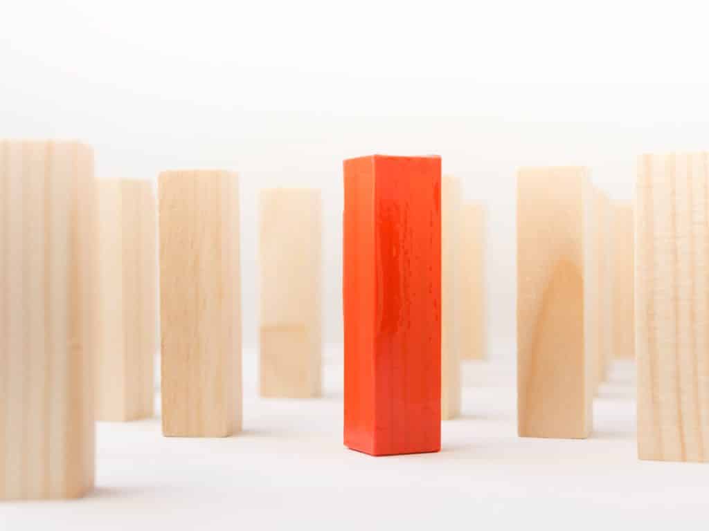Red wooden brick surrounded by normal ones close-up