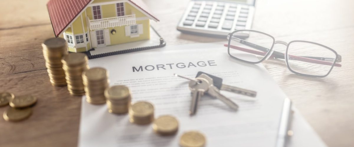 Mortgage contract for the purchase or sale of an apartment house or real estate. Work desk with contract coins model house calculator and pen.