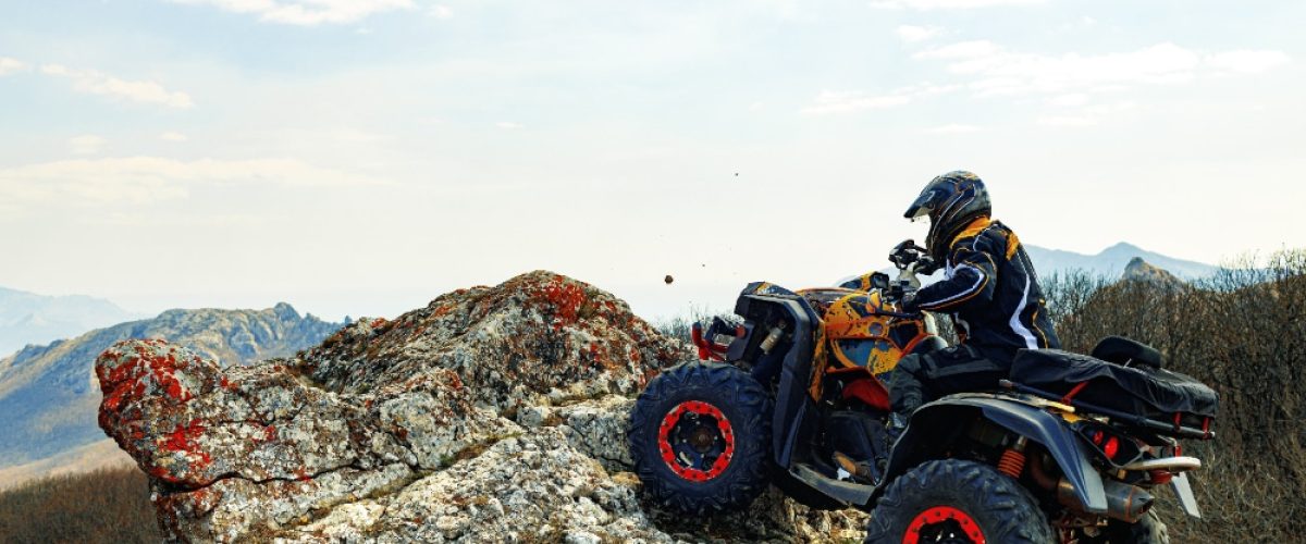 Man in helmet sitting on atv quad bike in mountains