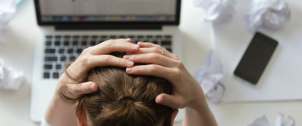 avatar Portrait of a woman grabbing head at desk near the laptop