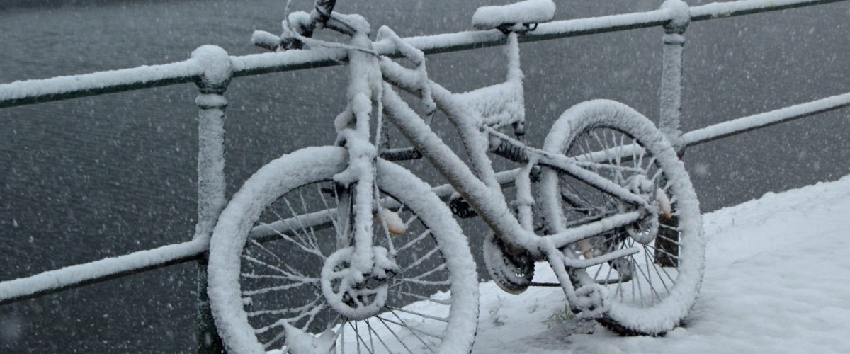Bicycle leaned against a fence covered in snow