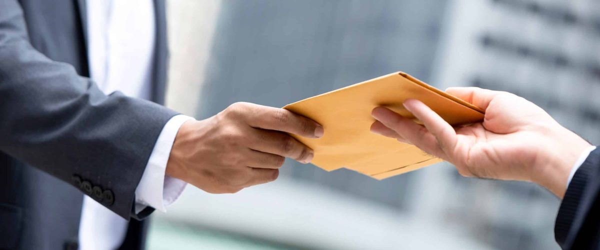 close-up-portrait-businessman-hand-recieving-yellow-envelope-urban-city-background-min