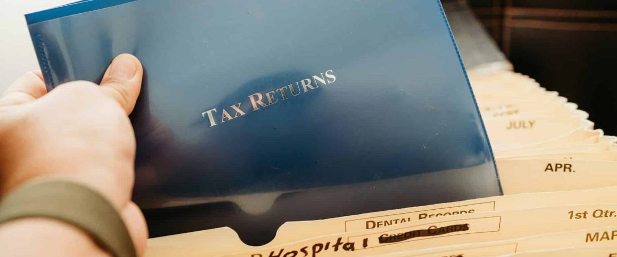 hand holding a file with a label called "Tax returns"