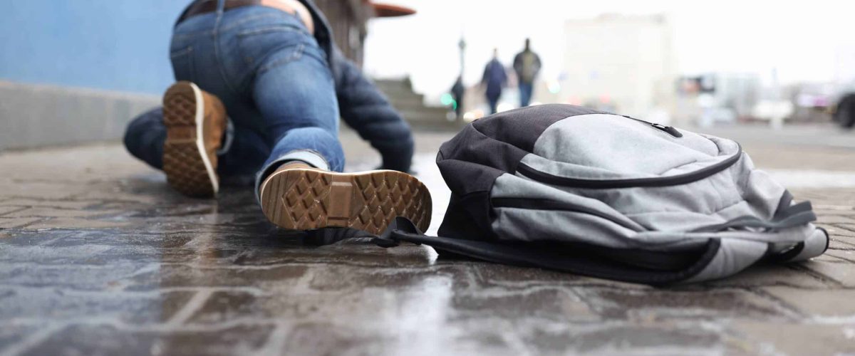 man-with-backpack-lying-slippery-sidewalk-after-fall-closeup