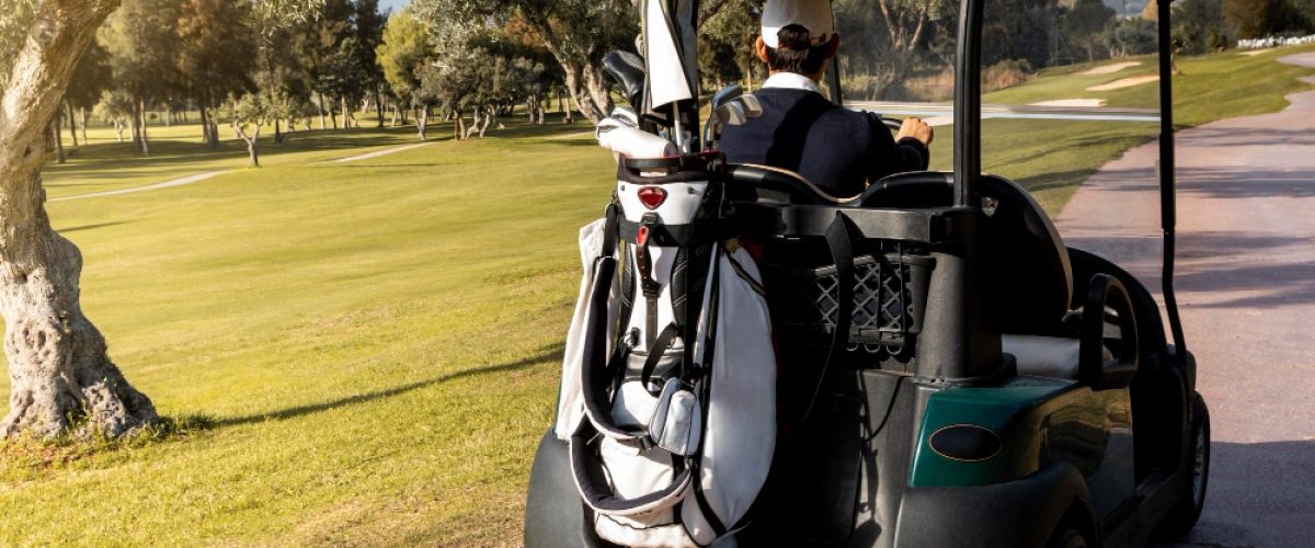 man-with-golf-cart-carrying-clubs