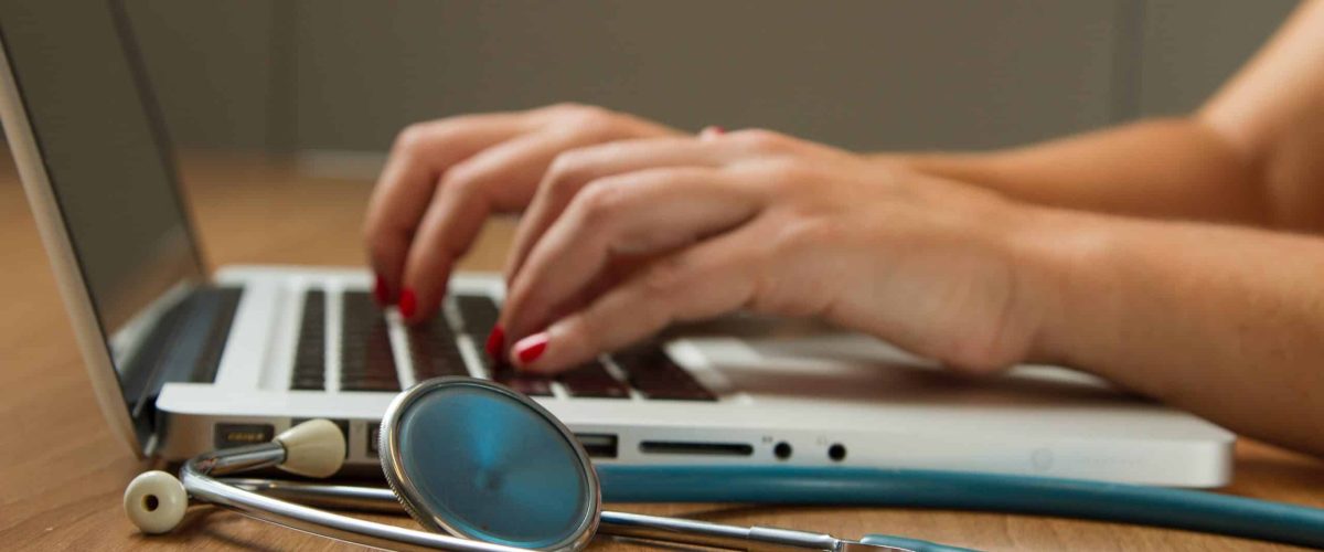 Image of doctor filling in medical records - laption, hands, stethoscope