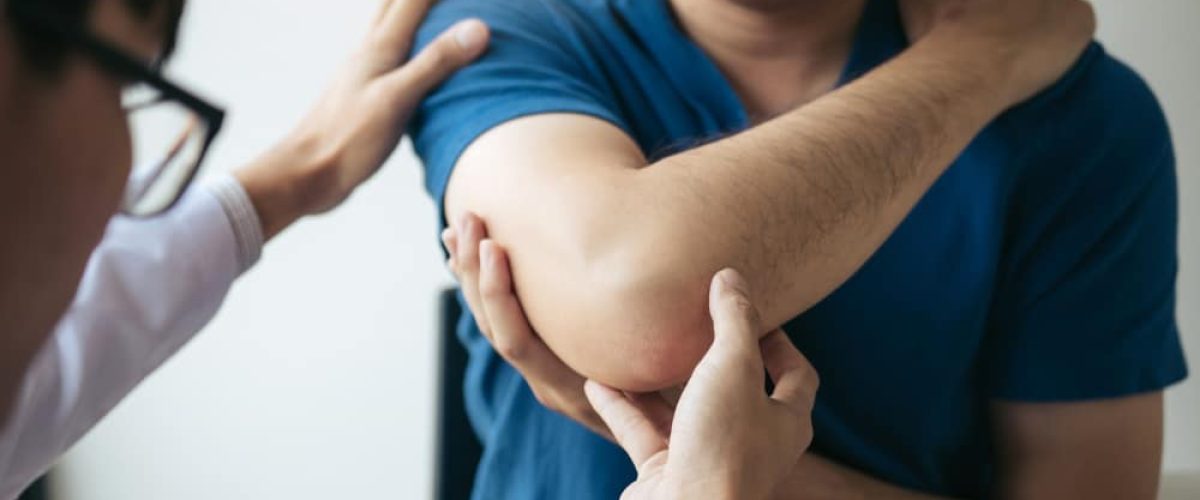 Image os a therapist examining a male patients's elbow.